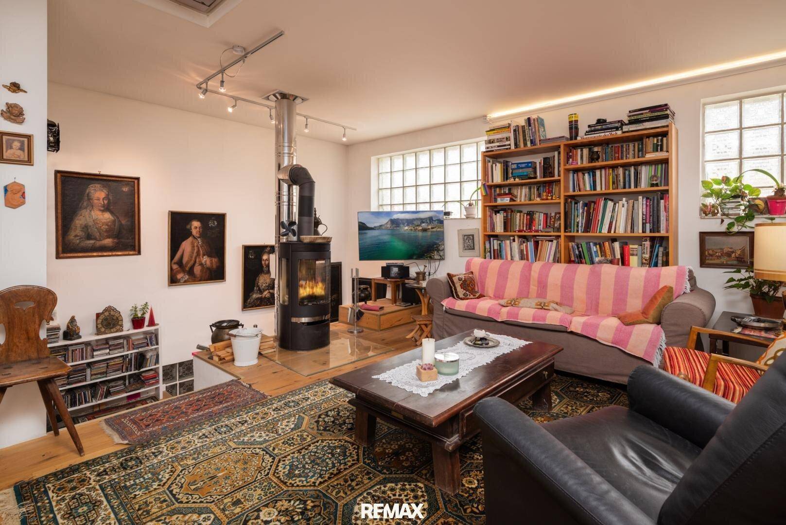 Gemütliches Wohnzimmer mit Kaminofen, Bücherregal und traditionellen Gemälden.