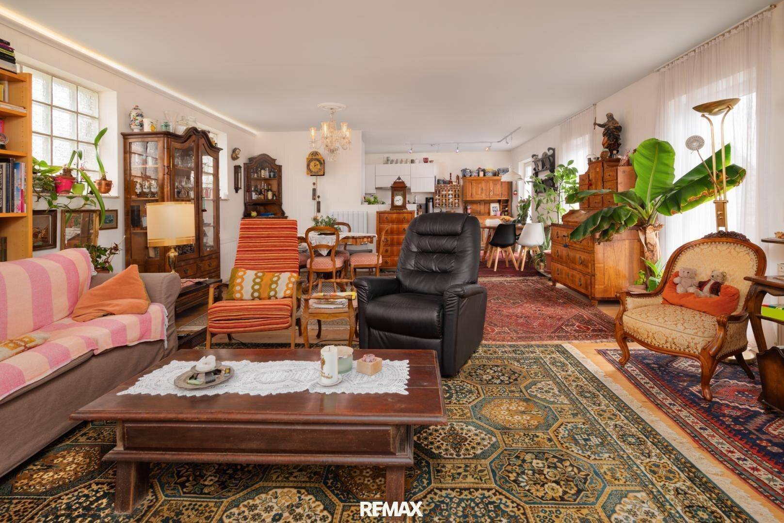 Großes Wohnzimmer mit vielfältigen Möbeln, Teppichen und vielen Pflanzen.