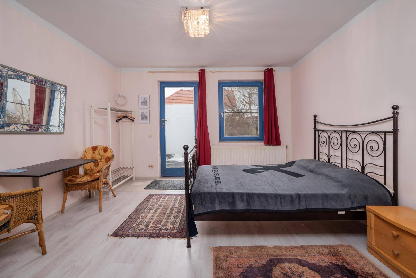 Helles Schlafzimmer mit Doppelbett, Teppich und blauen Fenstern.