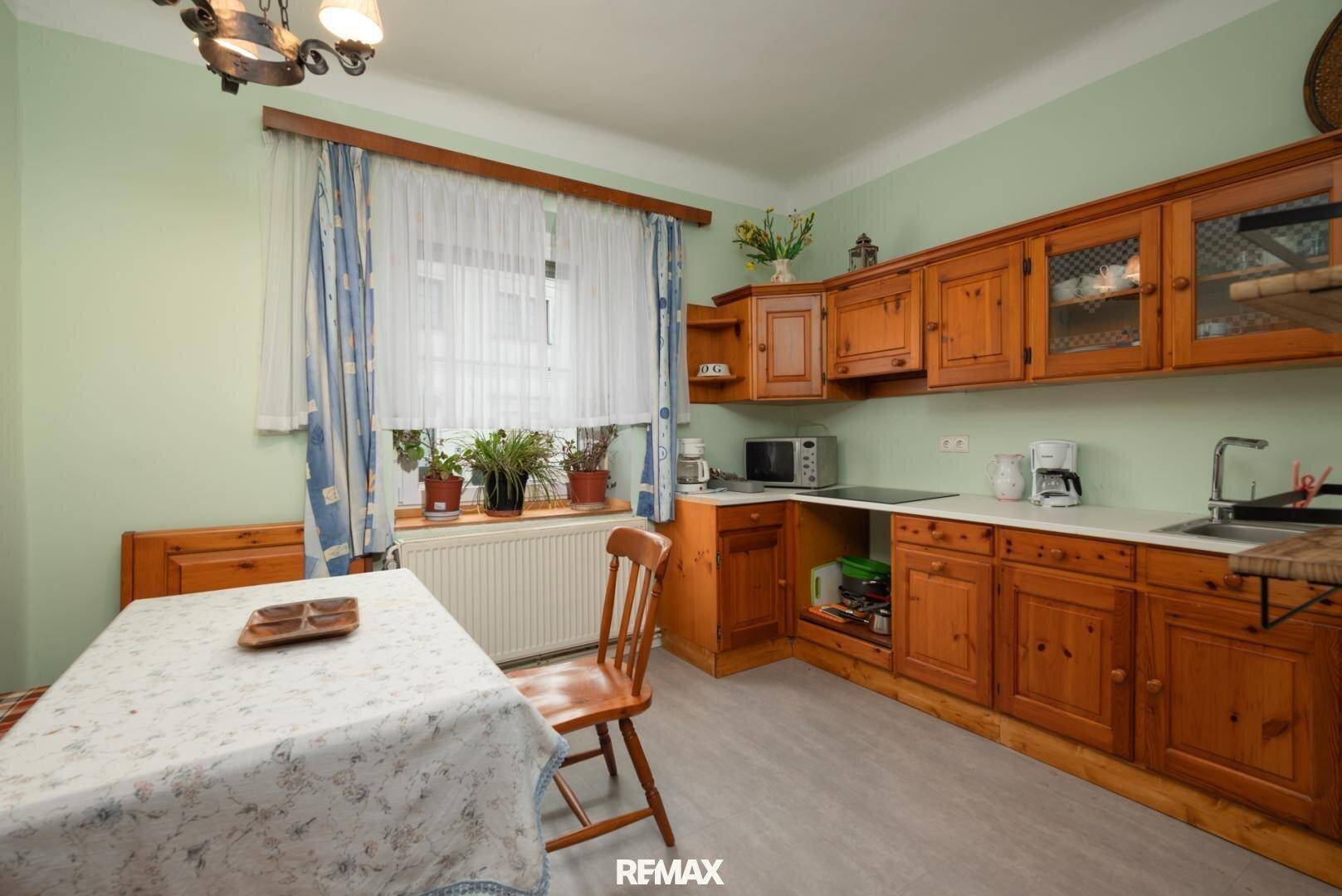 Traditionelle Holzküche mit Esstisch, Fenster und grünen Wänden.