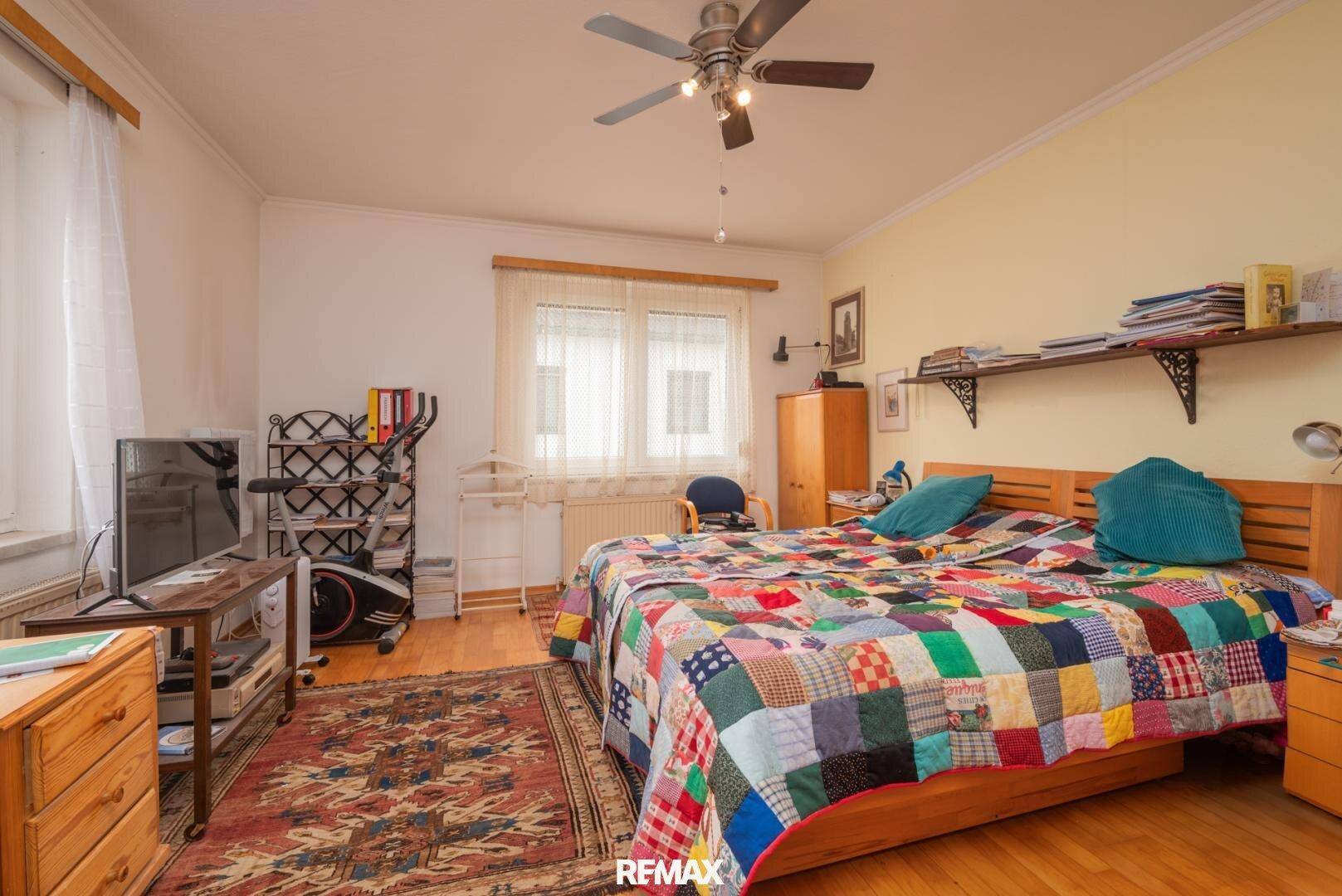 Geräumiges Schlafzimmer mit Doppelbett, Deckenventilator und Holzboden.