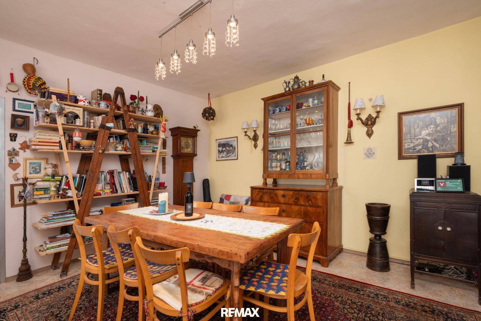 Geräumiges Esszimmer mit großem Holztisch, Bücherregal und traditionellen Möbeln.