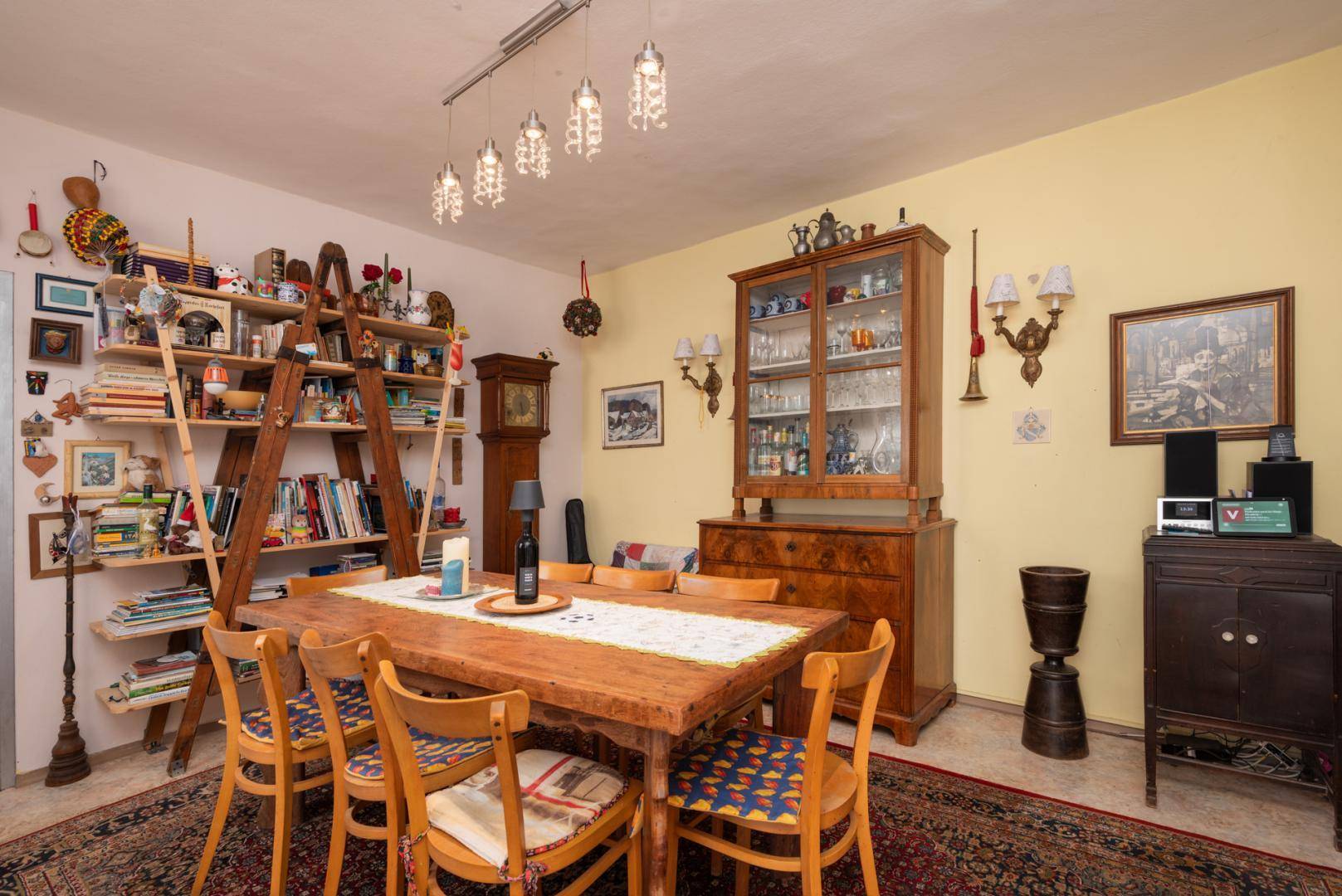 Geräumiges Esszimmer mit großem Holztisch, Vitrine und vielen Dekorationen.