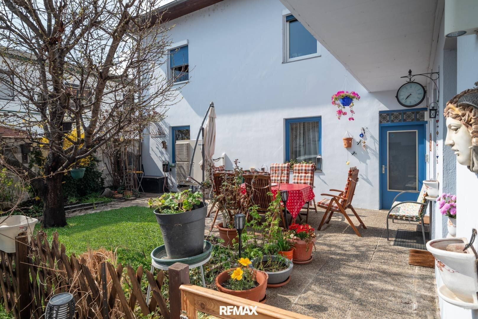 Gemütlicher Gartenbereich mit Terrasse, Sitzgelegenheiten und vielen Pflanzen.