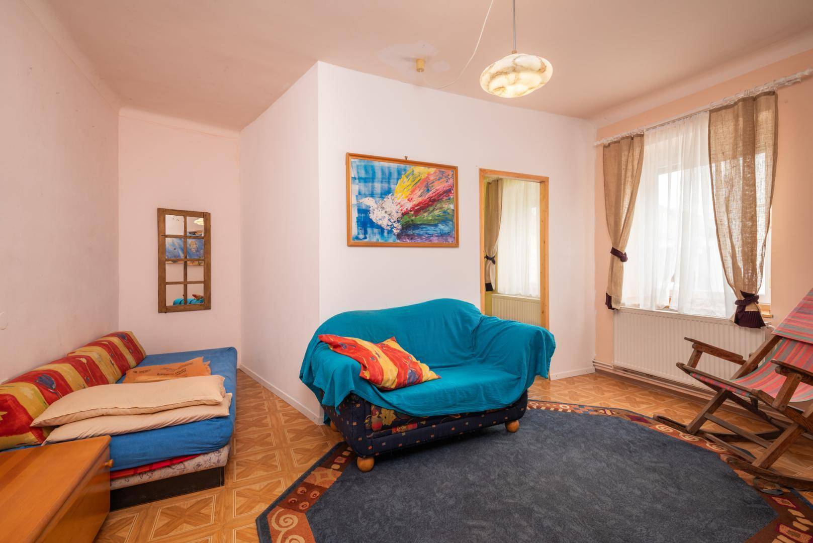 Wohnzimmer mit Sofa, Teppich und gemustertem Bodenbelag.