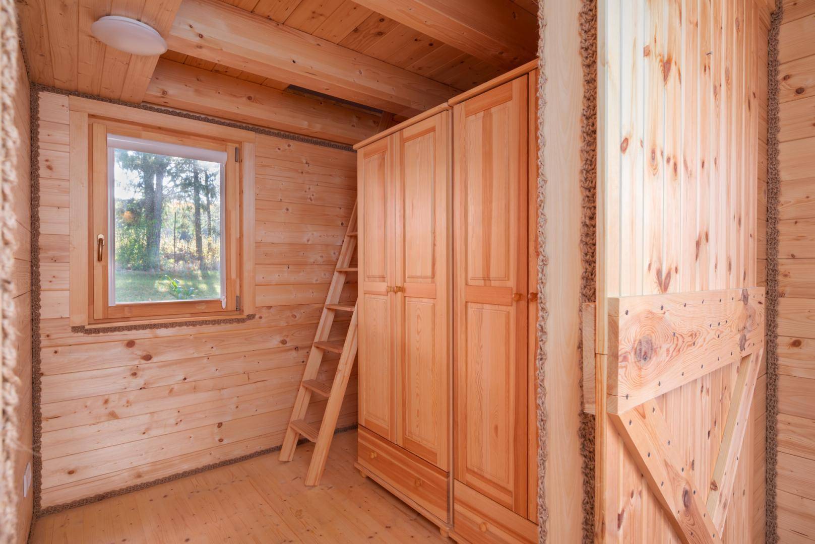 Gemütliches Schlafzimmer mit Holzvertäfelung, Fenster und integriertem Kleiderschrank, ideal für Gäste.