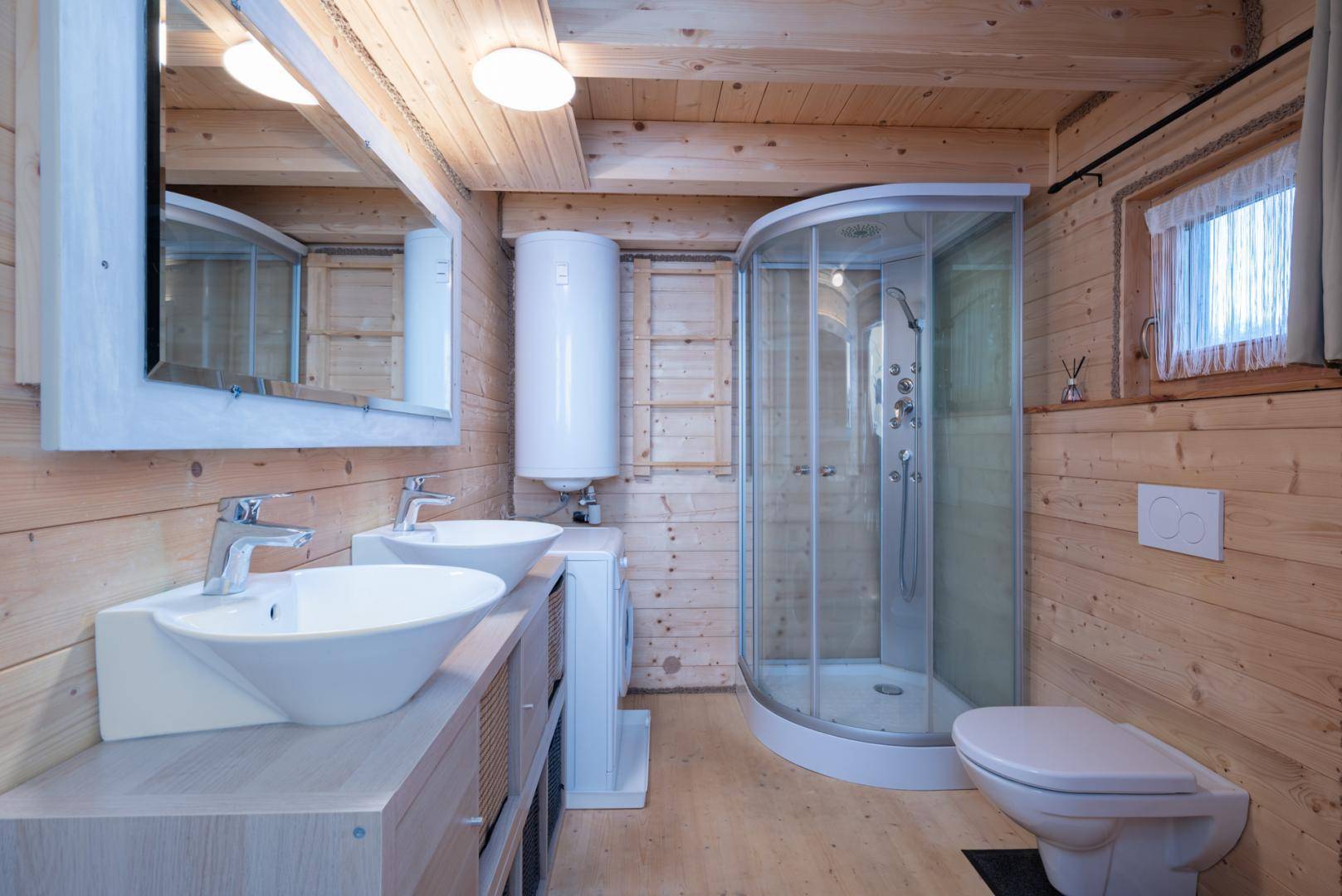 Modernes Badezimmer mit Doppelwaschbecken, Duschkabine und Holzvertäfelung, hell und funktional.
