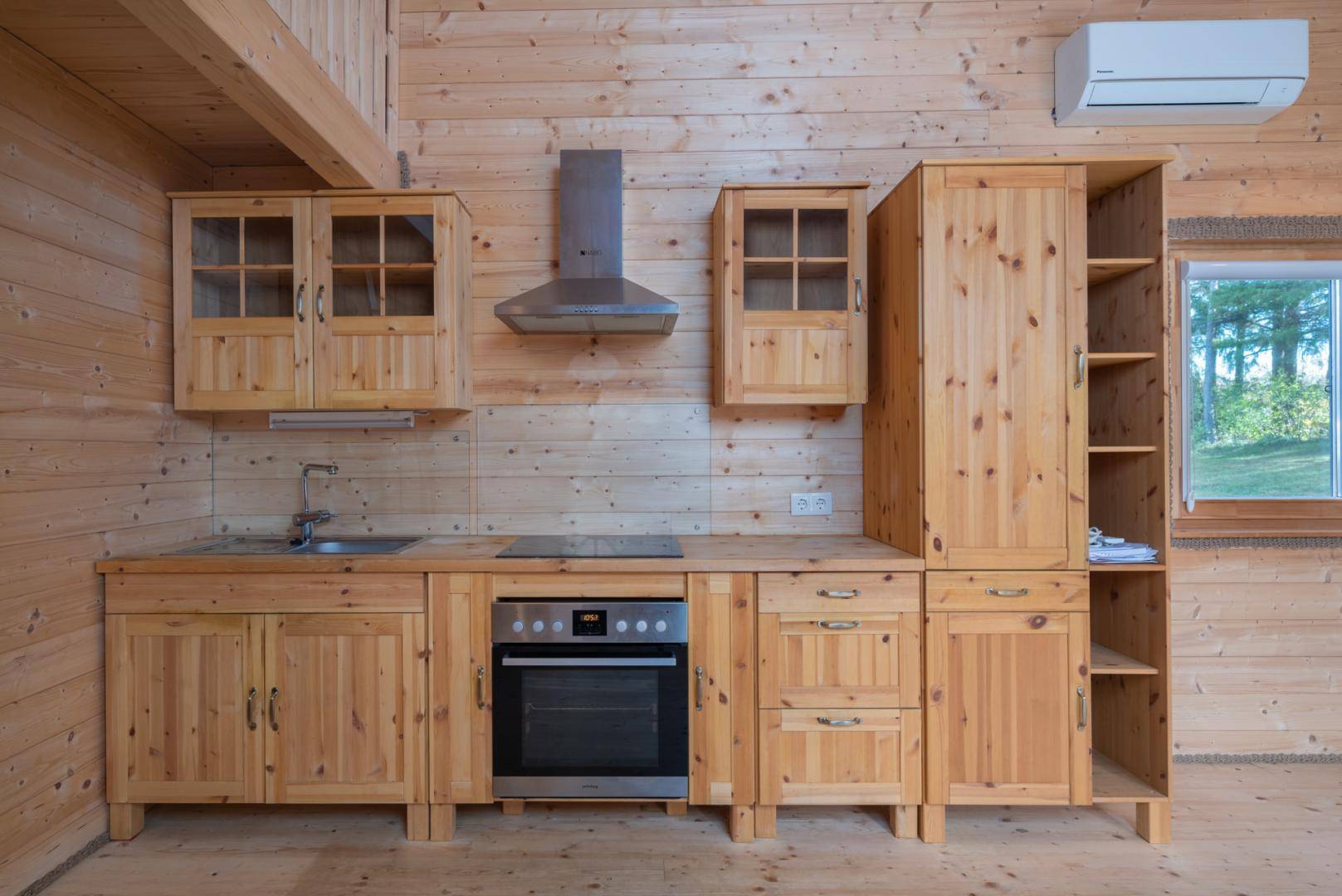 Rustikale Holzküche mit Einbauschränken, Kochfeld und Backofen in hellem Holzdesign und Klimaanlage.