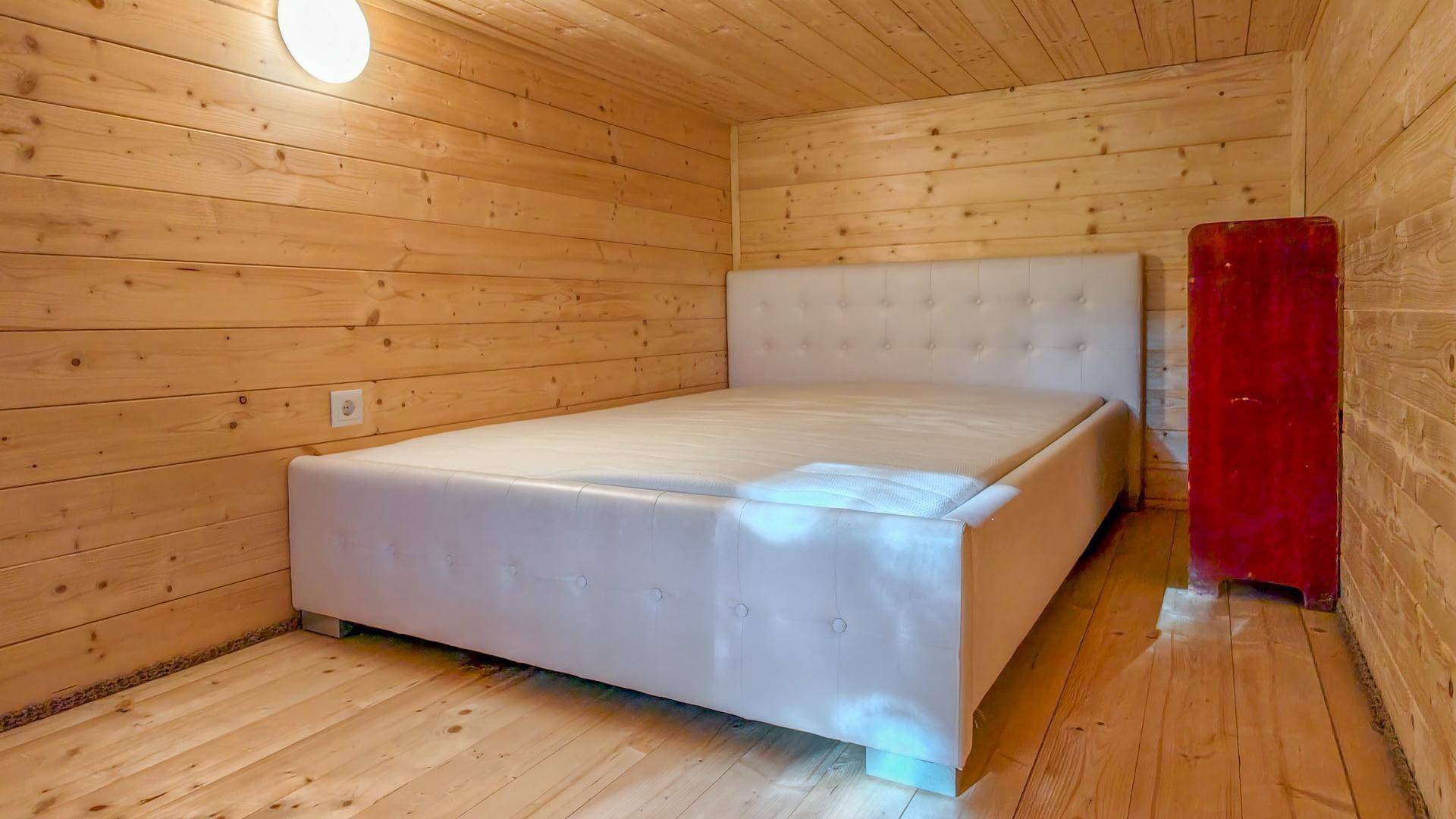 Schlafzimmer mit hellem Doppelbett und Holzvertäfelung, bietet eine gemütliche und warme Atmosphäre.