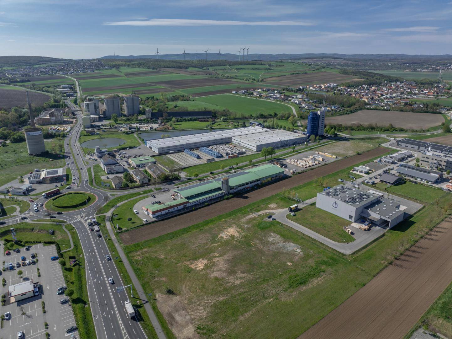 Weitläufige Luftaufnahme eines Gewerbegebiets mit Straßen, Kreisverkehr und verschiedenen Geschäftsgebäuden.