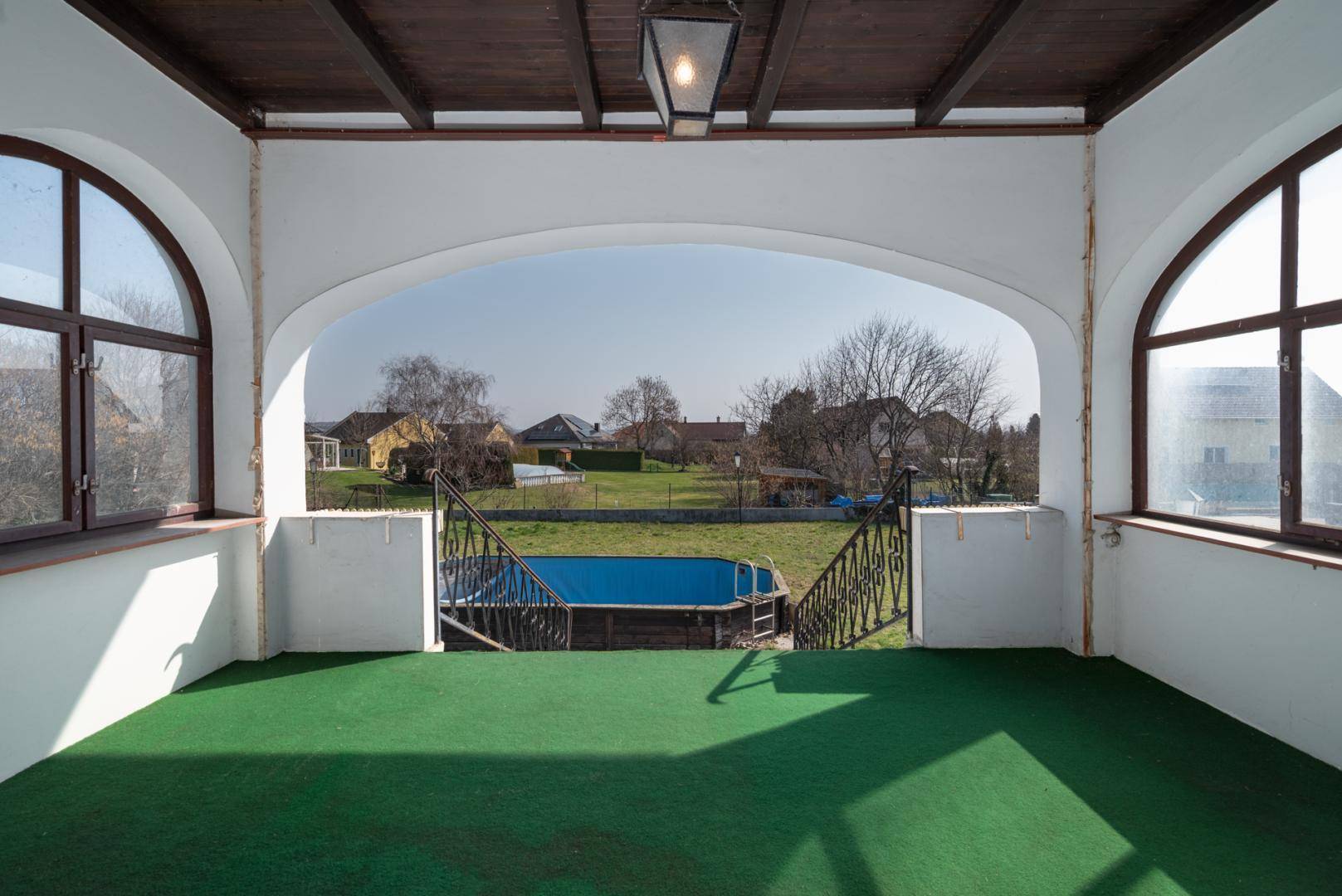 Überdachte Loggia mit Blick auf den Garten und den Aufstellpool, ideal für entspannte Stunden.