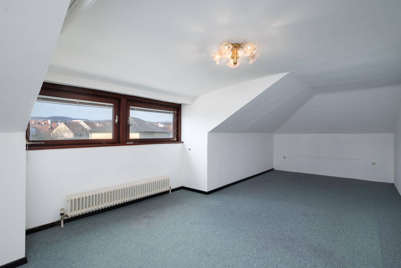 Geräumiger Raum im Dachgeschoss mit Teppichboden und Fenstern mit Blick auf die Umgebung.