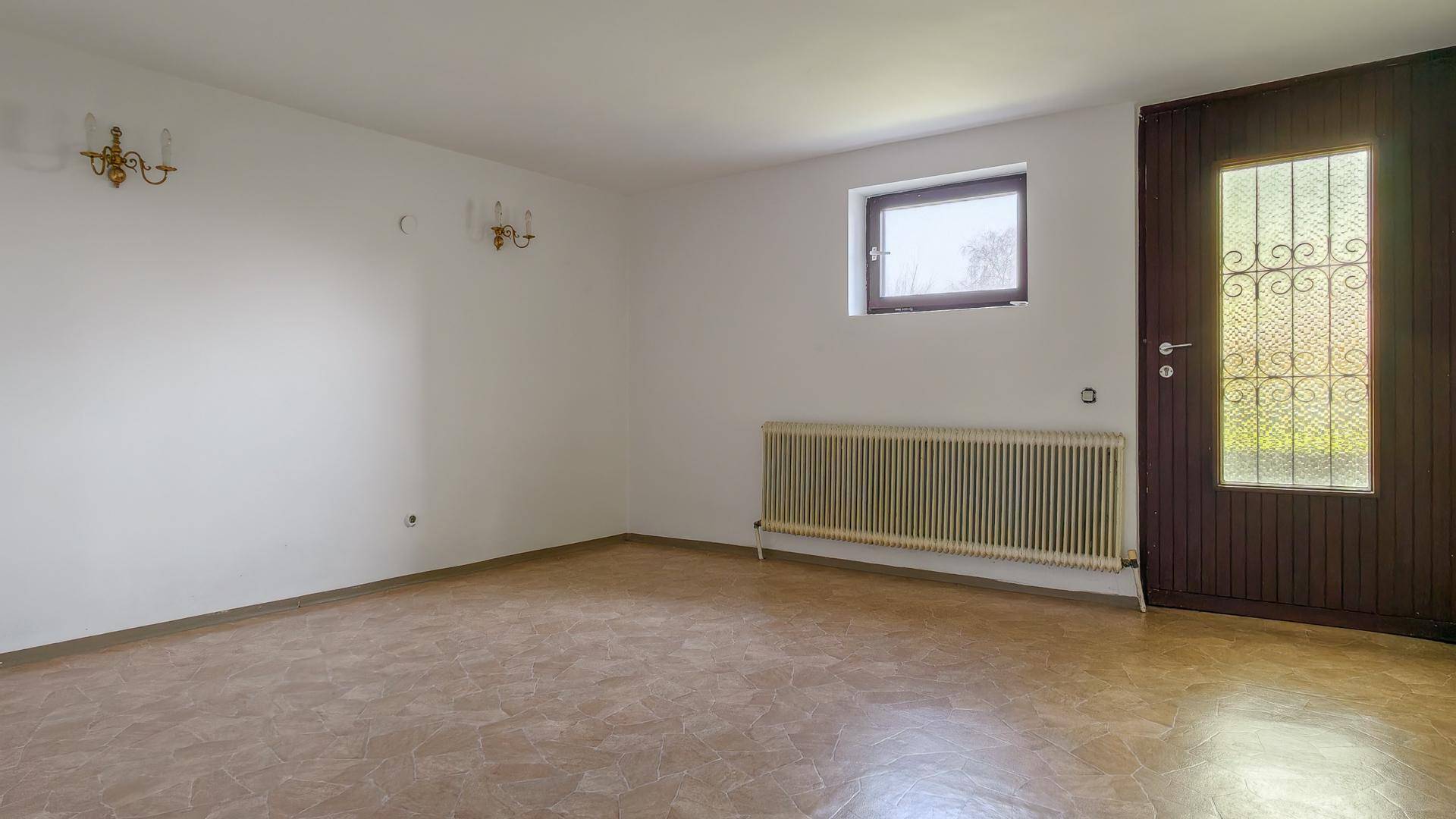 Heller Raum im Untergeschoss mit Fliesenboden und direktem Zugang nach draußen.