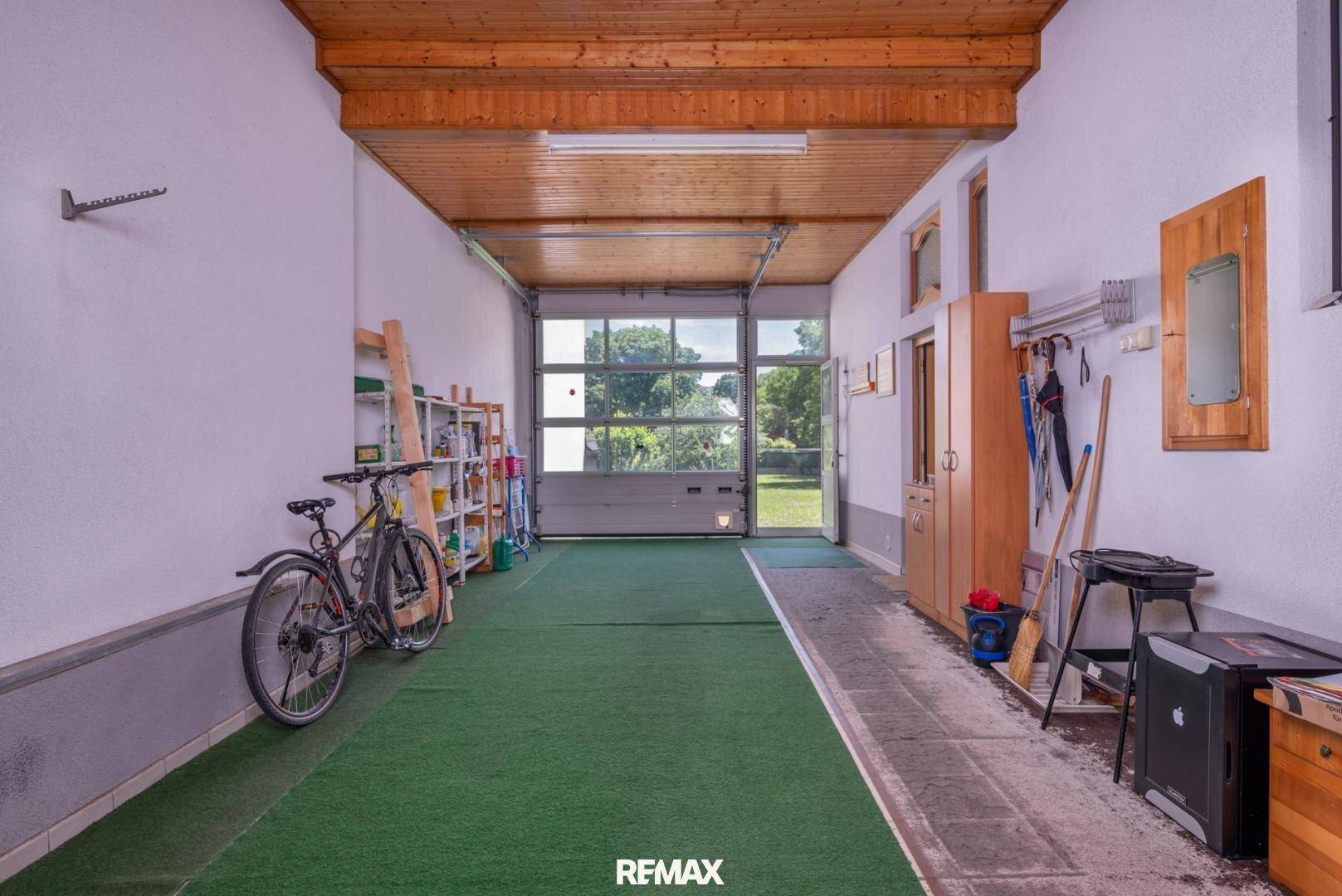 Geräumige Garage mit Rolltor zum Garten, Stauraum und Platz für Fahrräder.