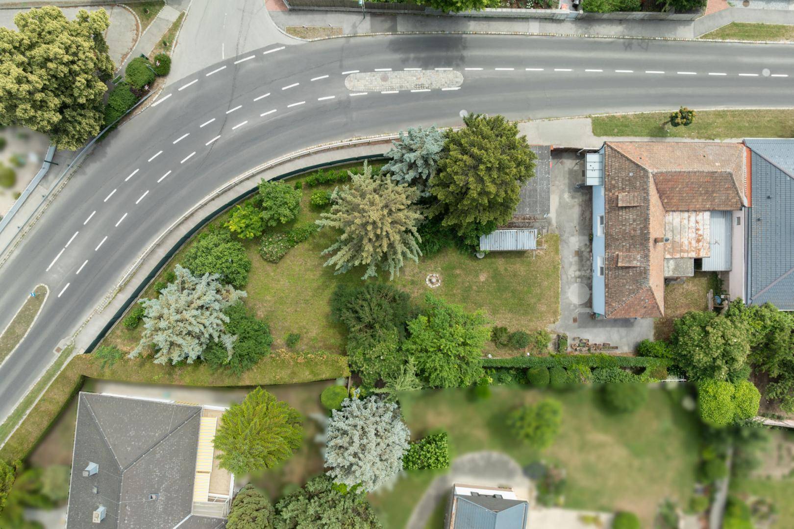 Luftaufnahme des Grundstücks mit Haus, großem Garten und angrenzender Straße.