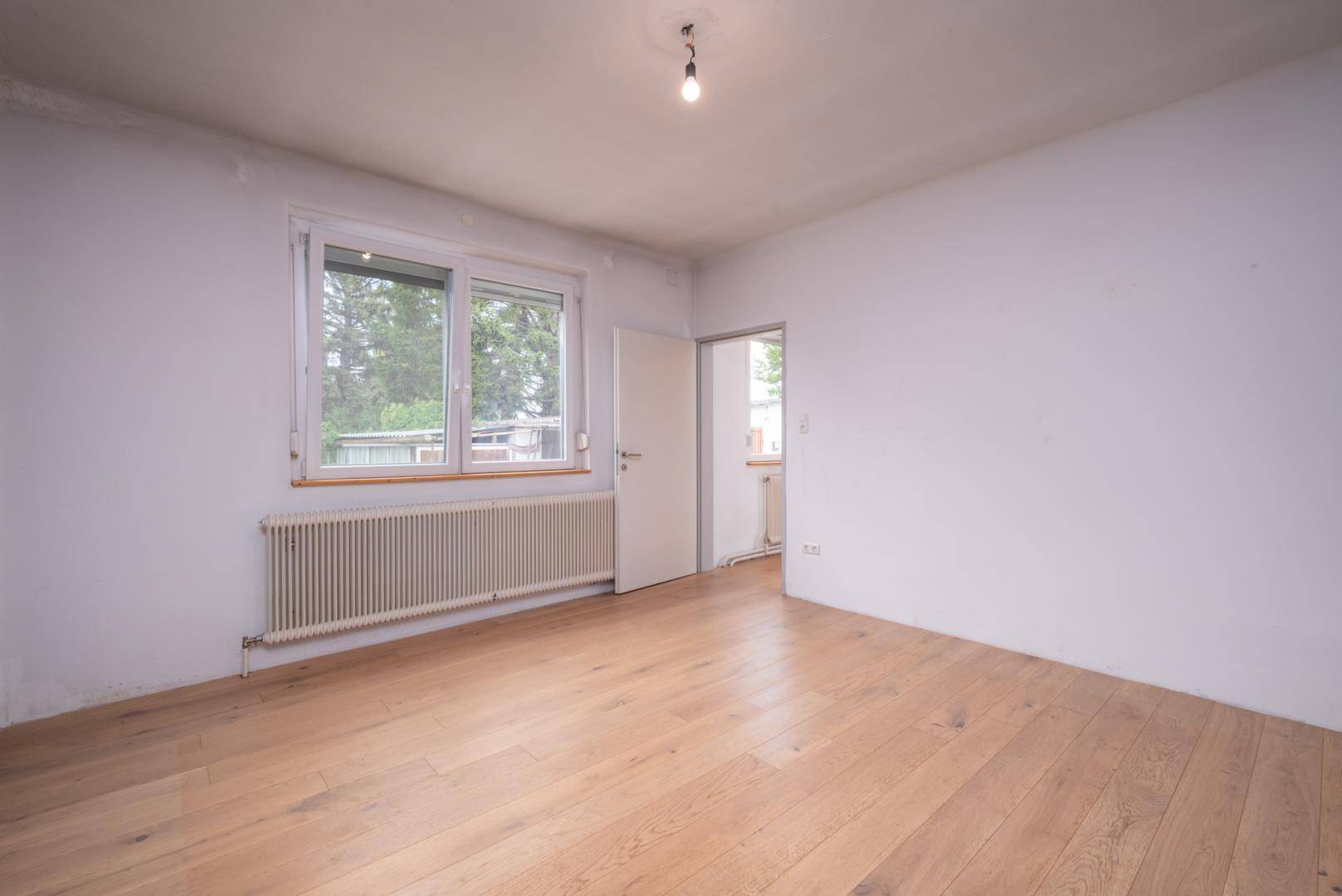 Weiteres leeres Schlafzimmer mit Holzboden, Fenster und Heizkörper, bietet viel Gestaltungspotenzial.