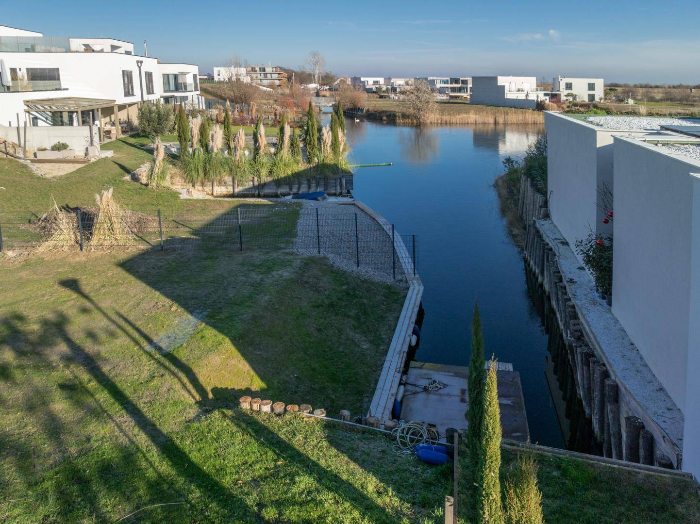 Blick auf den Kanal mit Anlegestellen, umgeben von gepflegten Grünflächen und modernen Häusern.