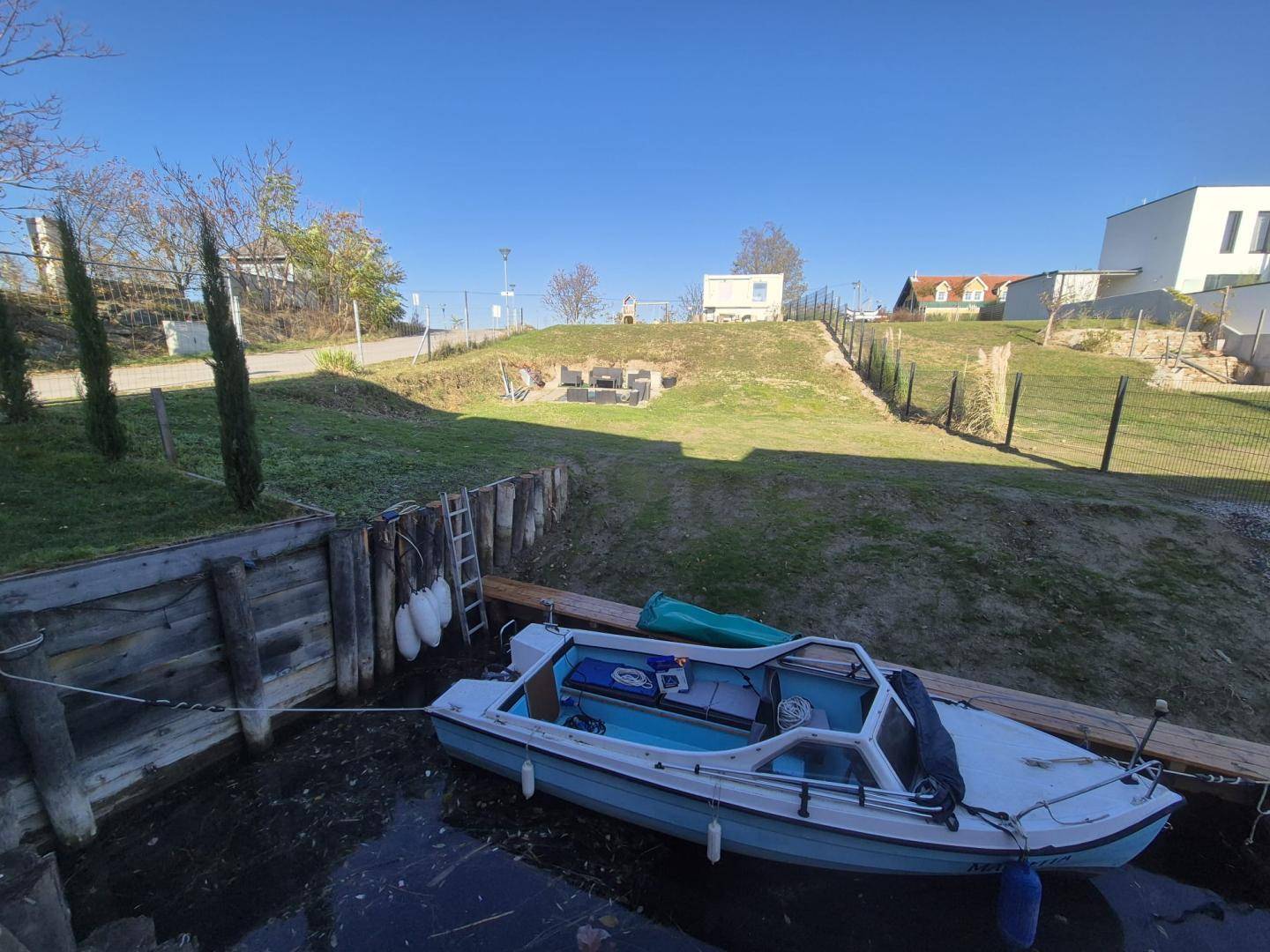 Kleines Boot am privaten Anlegesteg mit Blick auf die umliegende Landschaft und moderne Häuser.