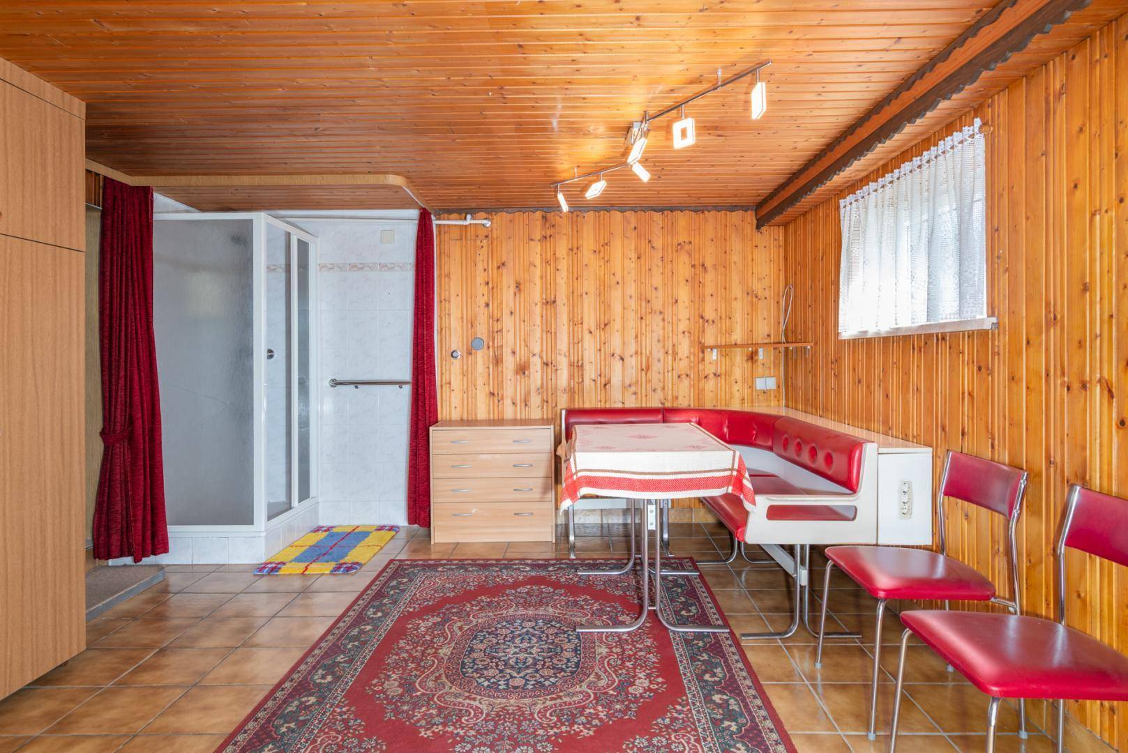 Rustikaler Hobbyraum im Keller mit Holzverkleidung, Sitzecke und integrierter Dusche.