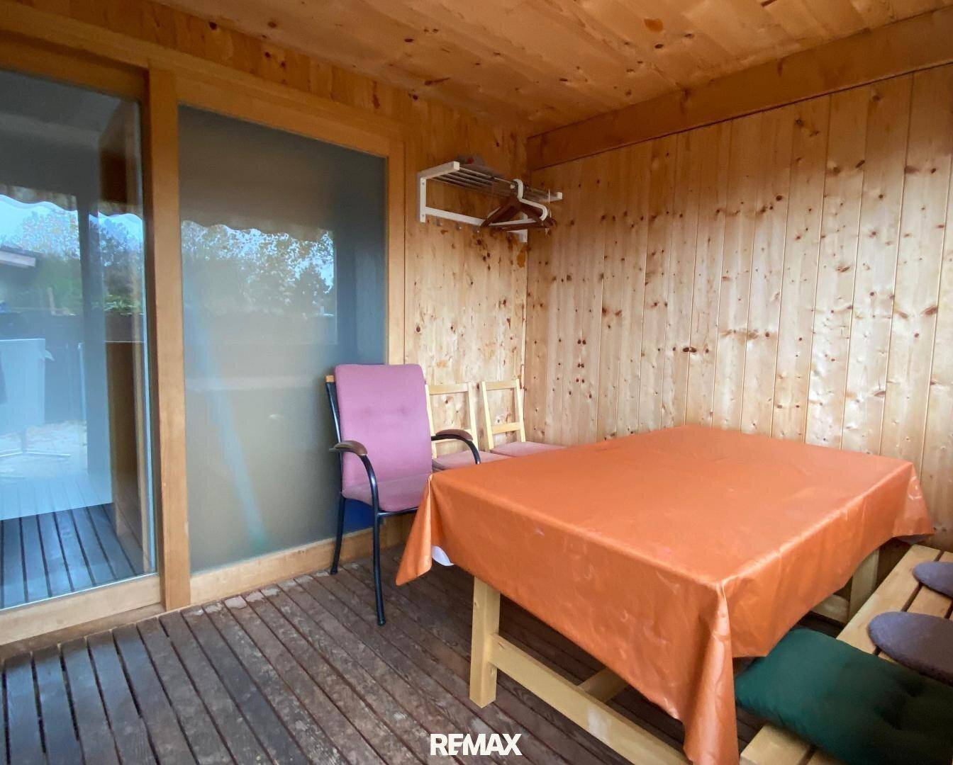 Gemütlicher Wintergarten mit Holzwänden, Holzboden und einem Tisch mit Stühlen.