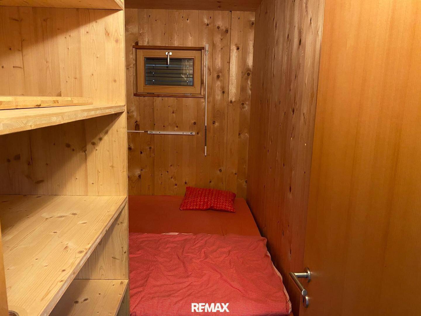 Gemütlicher Schlafbereich mit Einzelbett und Holzwänden.