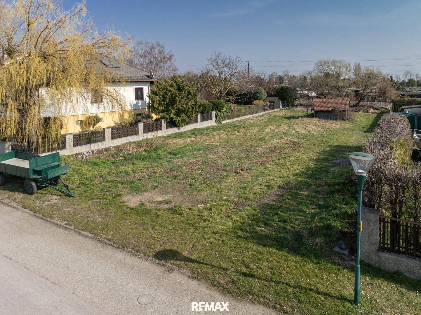 Blick über das unbebaute Grundstück von der Straße aus mit einem kleinen Schuppen im Hintergrund.
