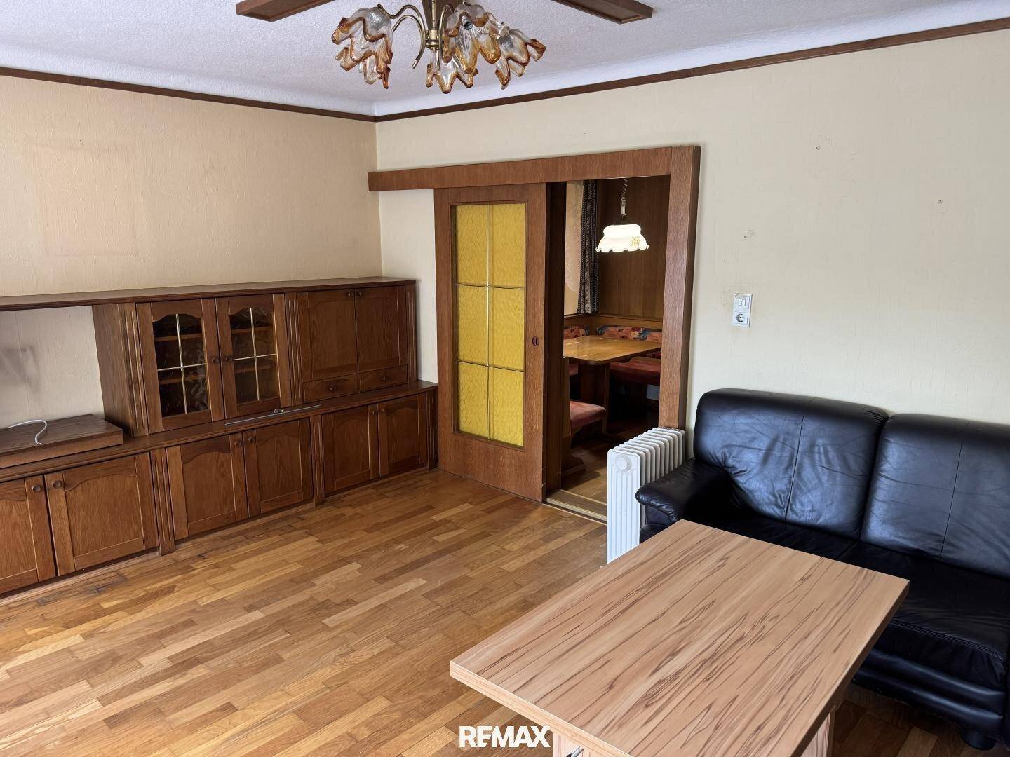 Wohnzimmer mit Holzparkett, Ledersofa und traditionellen Holzmöbeln, strahlt eine warme Atmosphäre aus.