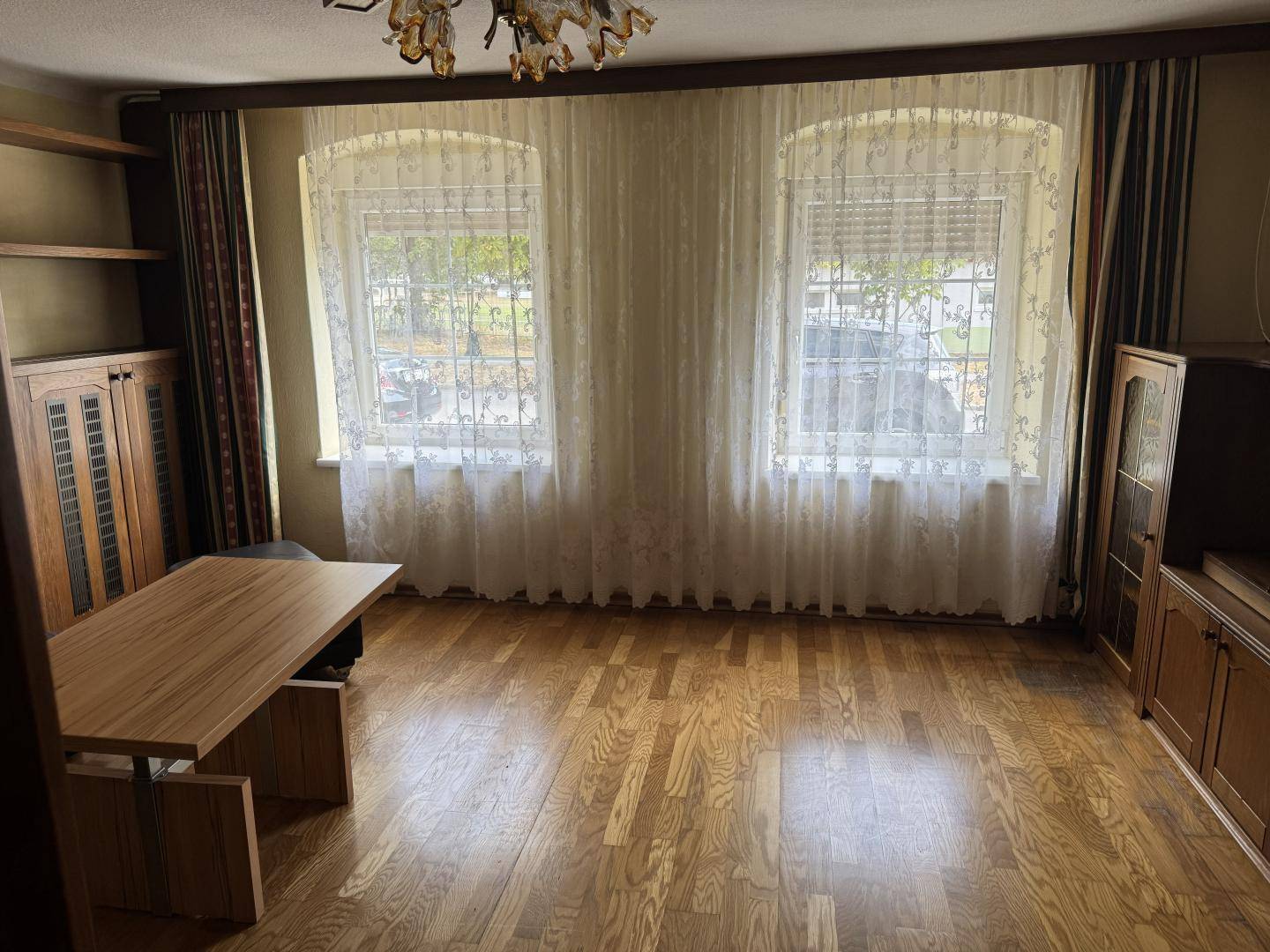 Geräumiges Zimmer mit Holzfußboden, zwei Fenstern und traditionellen Holzmöbeln.