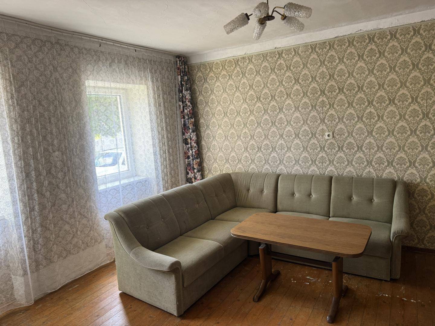 Gemütliches Wohnzimmer mit Ecksofa, Holztisch und gemusterter Tapete.