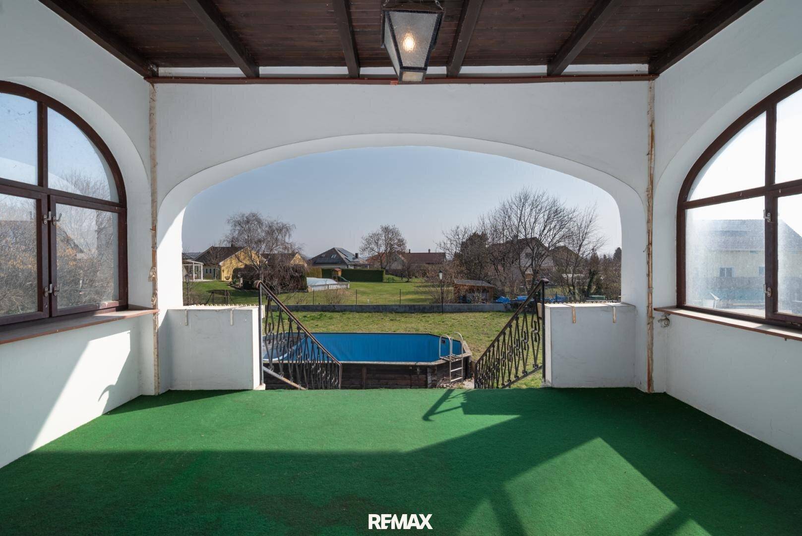 Überdachte Loggia mit Blick auf den Garten und den Aufstellpool, ideal zum Entspannen.