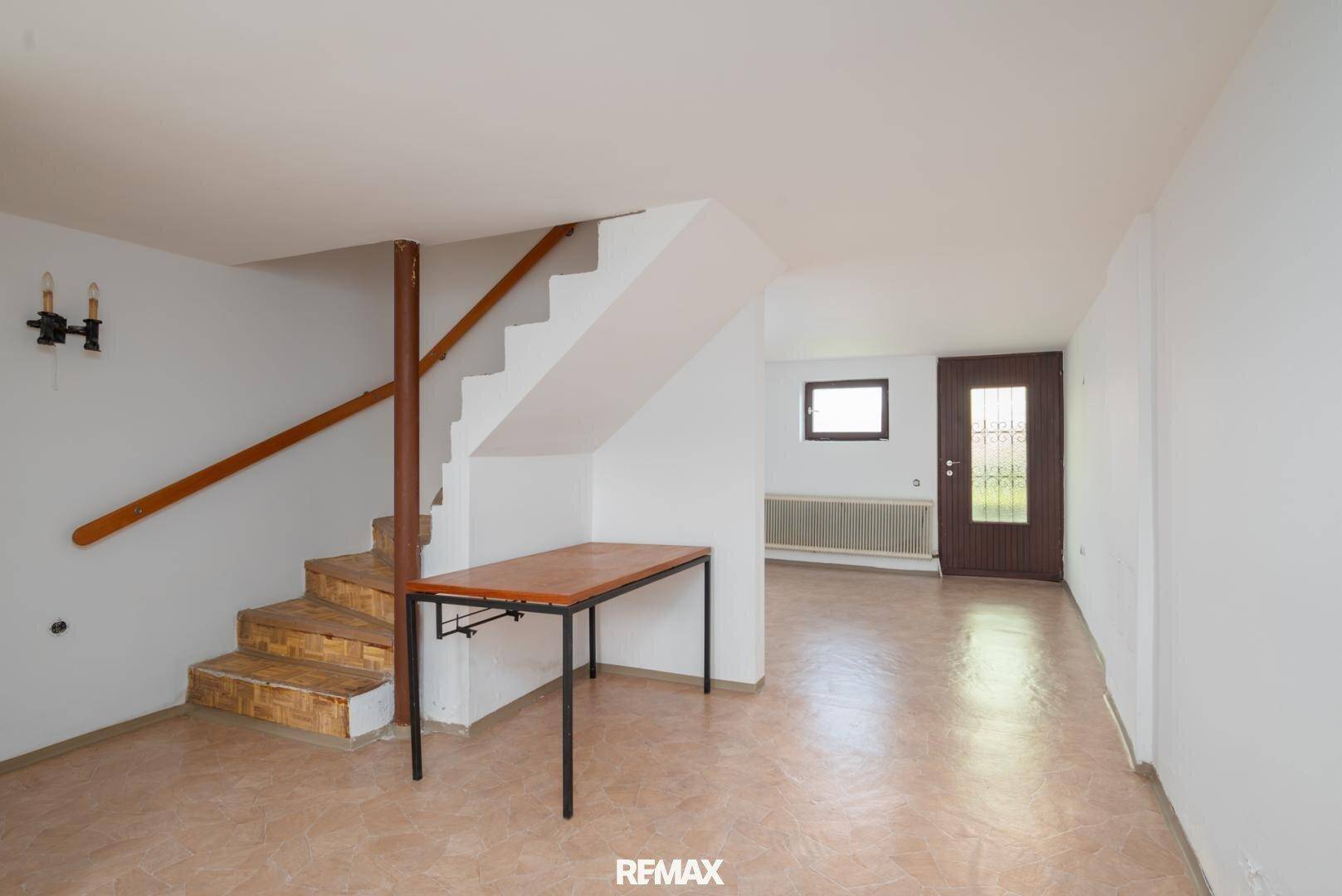 Geräumiger Kellerraum mit Treppe, Fliesenboden und Zugang nach draußen.