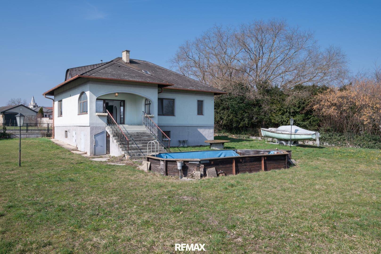 Hinterhof mit Rasenfläche, einem Aufstellpool und Blick auf das Haus.
