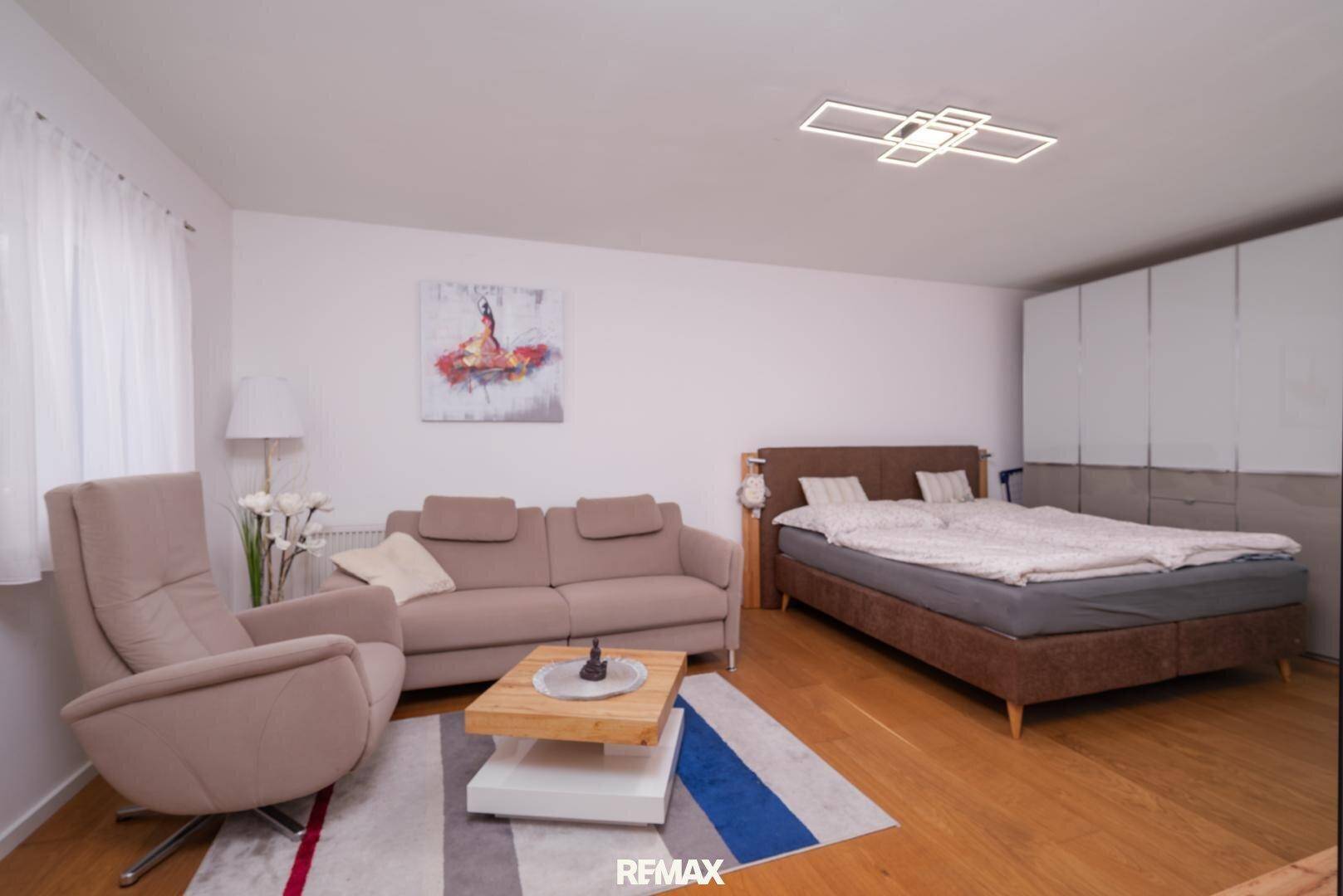 Kombinierter Schlaf- und Wohnbereich mit Doppelbett, Sofa und Holzfußboden.