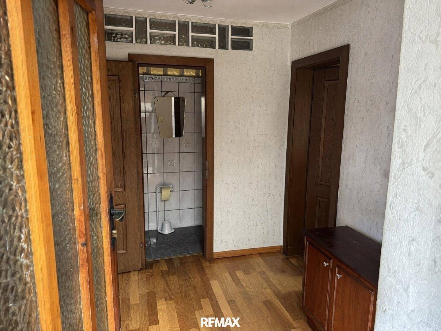 Flur mit Holzfußboden und Zugang zu einem gefliesten Gäste-WC.