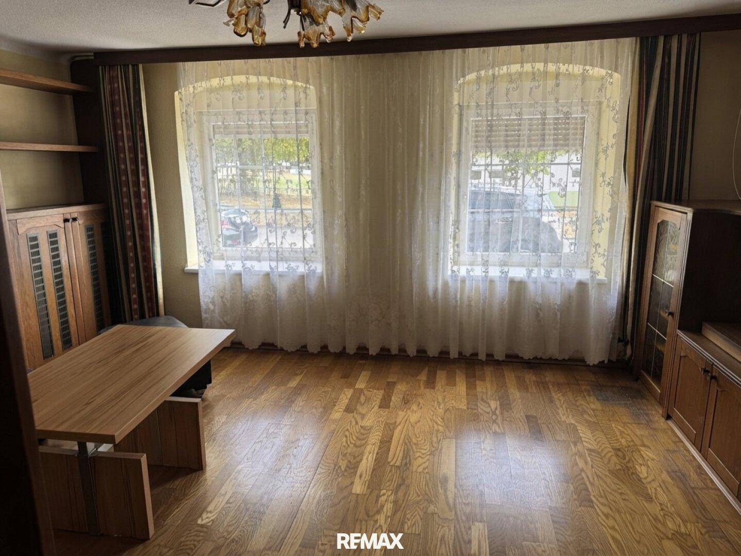 Geräumiges Zimmer mit Holzparkett, großen Fenstern und traditionellen Möbeln.