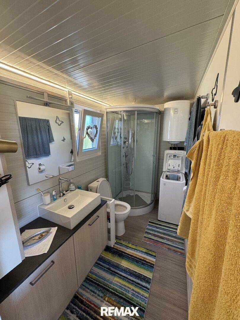 Modernes Badezimmer mit Duschkabine, Waschbecken, Toilette und Waschmaschine.
