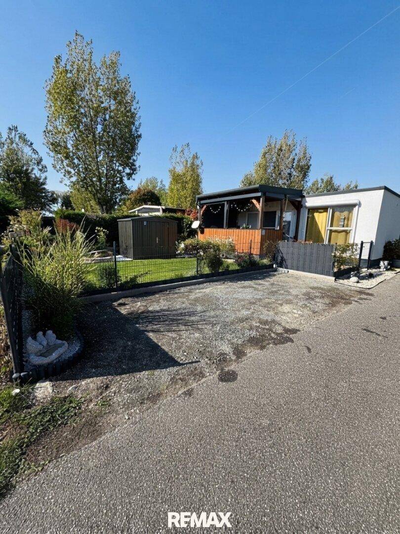Außenansicht des Hauses mit einem gepflasterten Parkplatz und angrenzendem Gartenbereich.