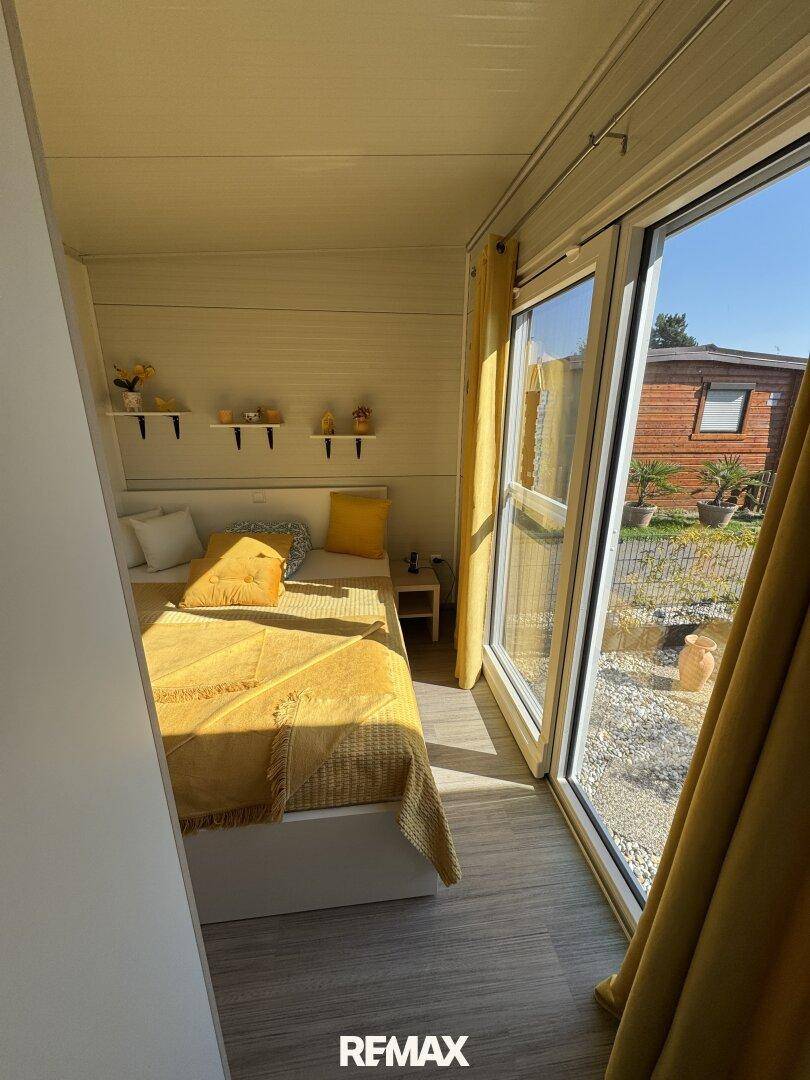 Helles Schlafzimmer mit zwei Einzelbetten, gelber Bettwäsche und direktem Zugang zum Außenbereich.