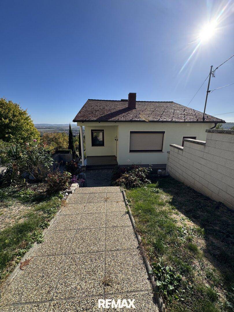 Vorderansicht des Hauses an einem sonnigen Tag mit einem gepflasterten Weg zum Eingang.