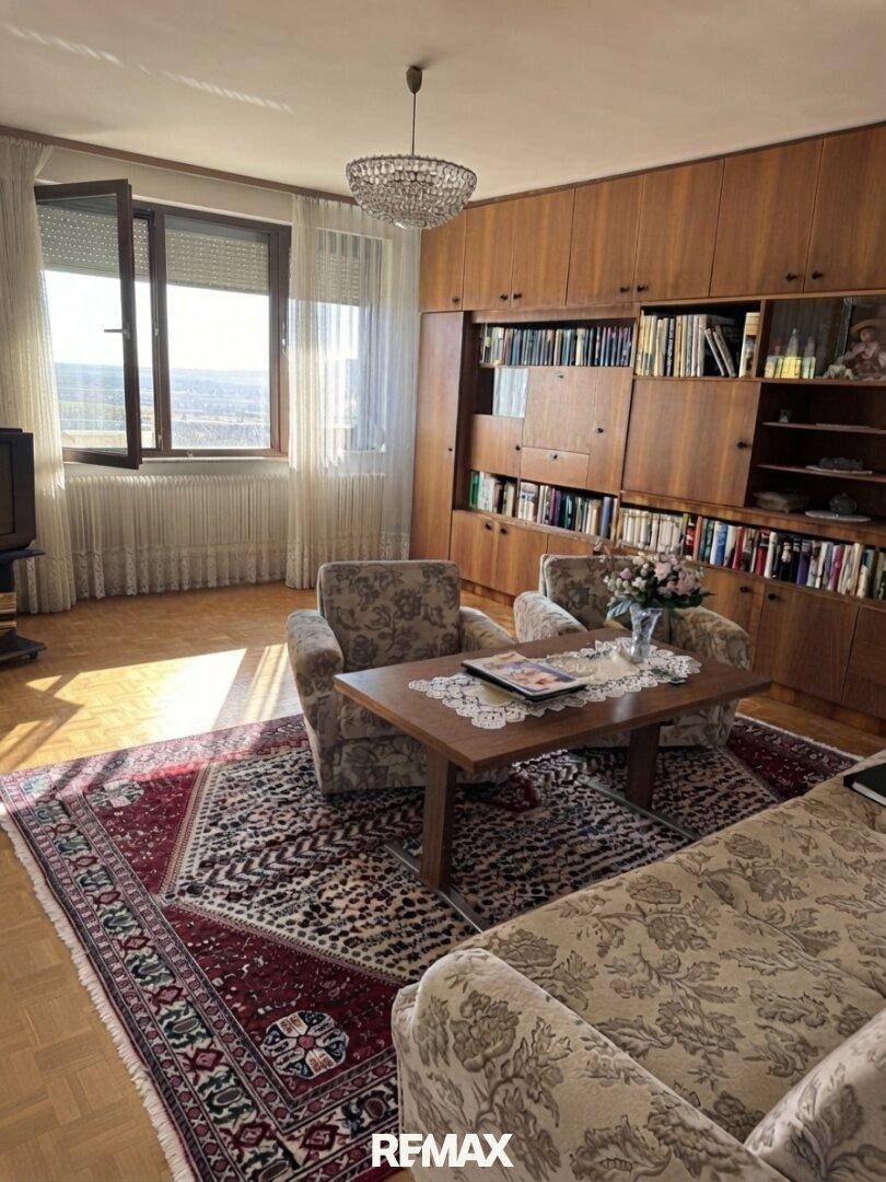 Gemütliches Wohnzimmer mit Parkettboden, Einbauschränken und einem weiten Ausblick durch das Fenster.