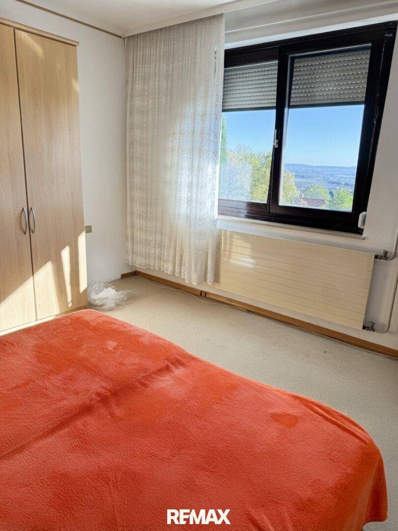 Schlafzimmer mit Teppichboden, einem Bett und einem großen Fenster mit weitem Ausblick.