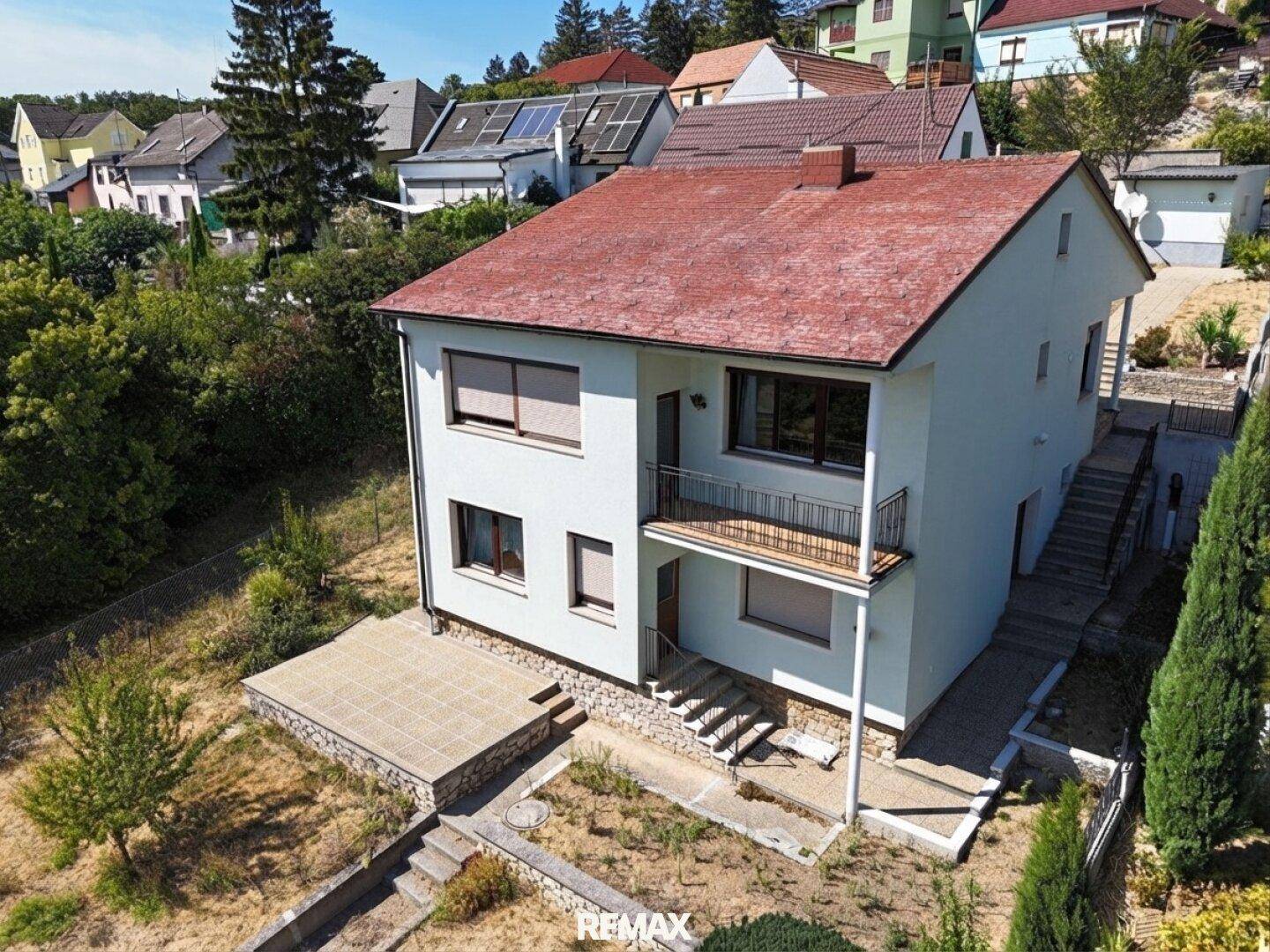 Luftaufnahme des Hauses von einer anderen Perspektive mit Balkon und Terrasse im Vordergrund.