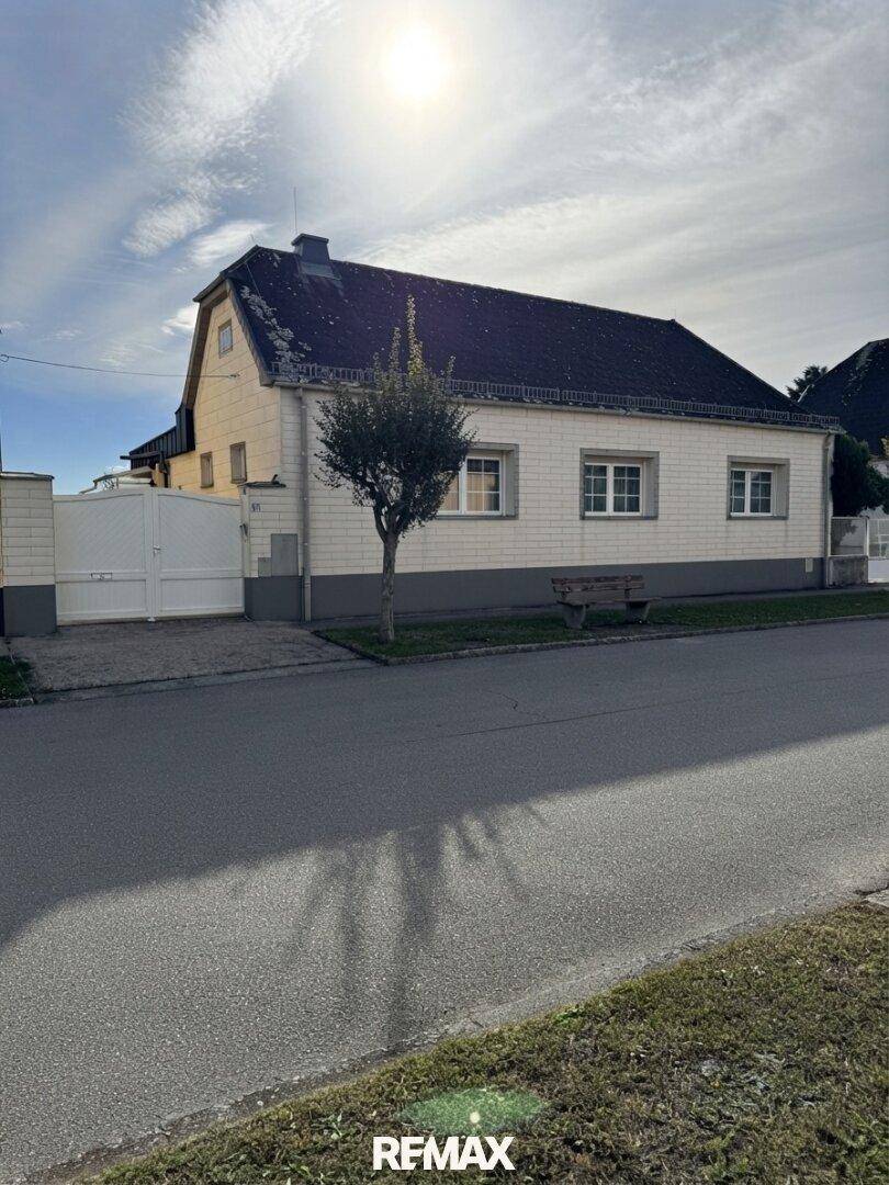 Ansicht des Hauses von der Straße mit weißer Fassade, Satteldach und einem kleinen Vorgartenbereich.