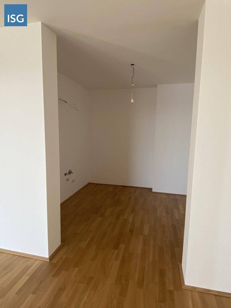 Heller, leerer Innenraum mit Holzboden und weißen Wänden, bereit zur Gestaltung.