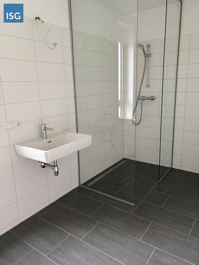 Modernes Badezimmer mit ebenerdiger Dusche, weißen Wandfliesen und einem Einzelwaschbecken.