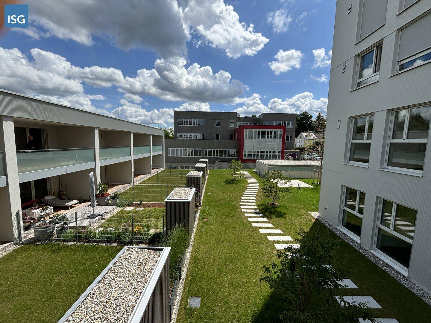 Weitläufiger Außenbereich mit gepflegten Rasenflächen, Trittplatten und modernen Wohngebäuden.