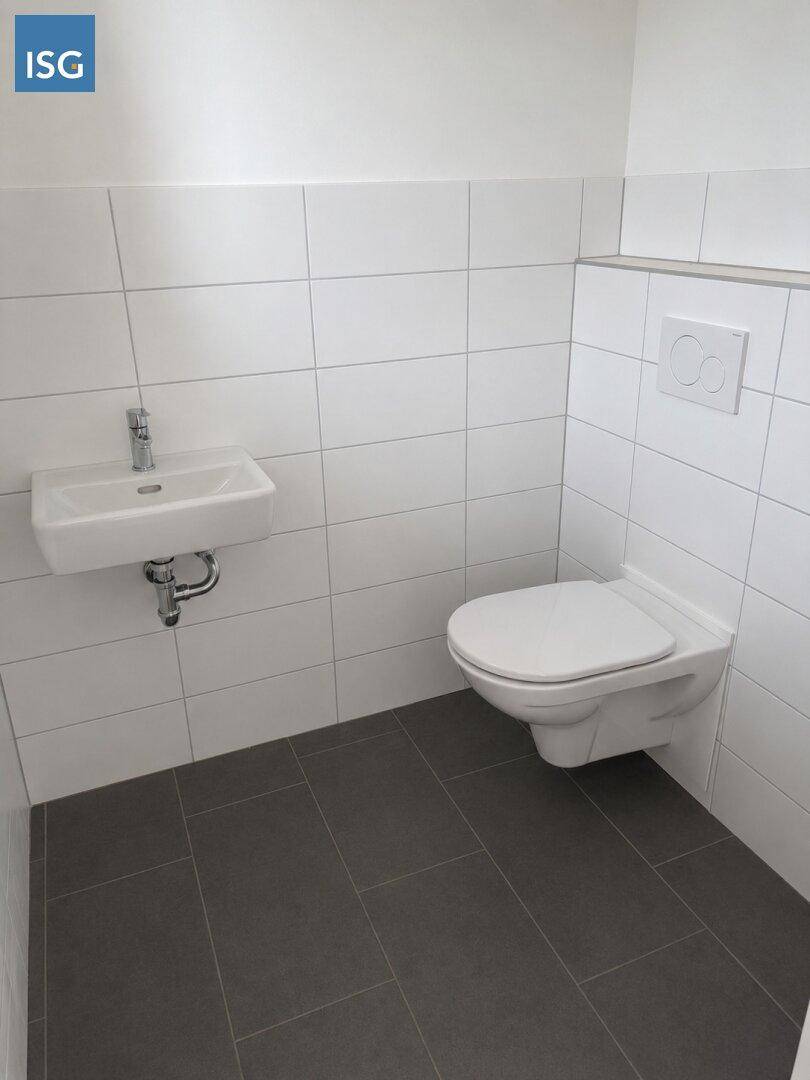 Kleines, helles Gäste-WC mit wandhängender Toilette, Waschbecken und grauen Bodenfliesen.