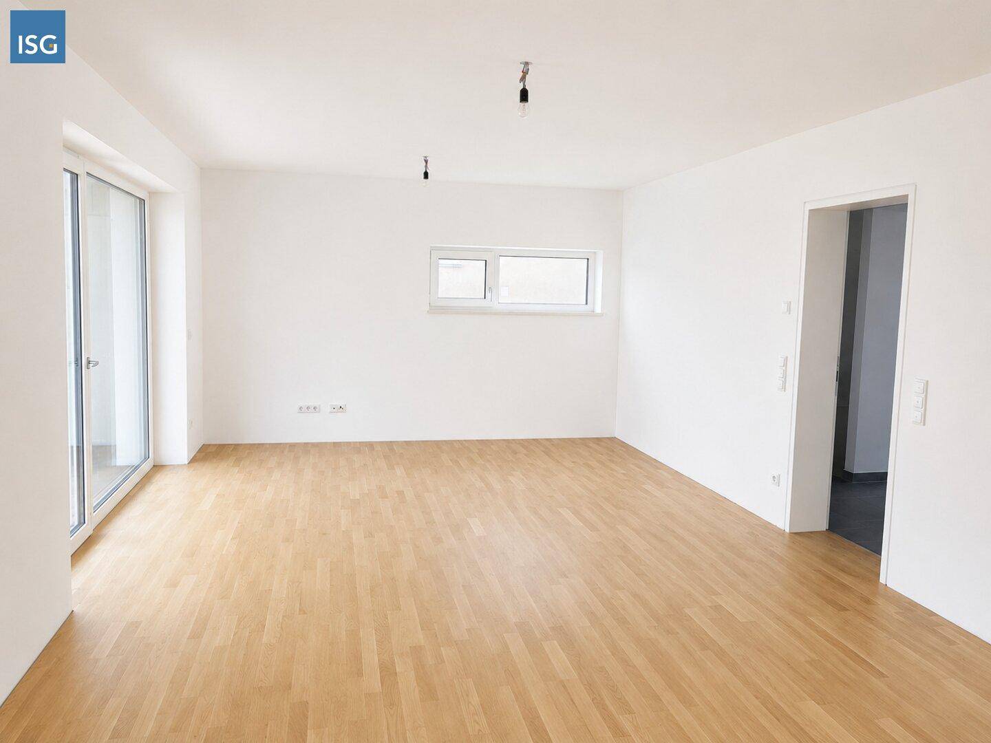 Helles, leeres Wohnzimmer mit großen Fenstern und hellem Holzparkettboden, bereit zur individuellen Gestaltung.