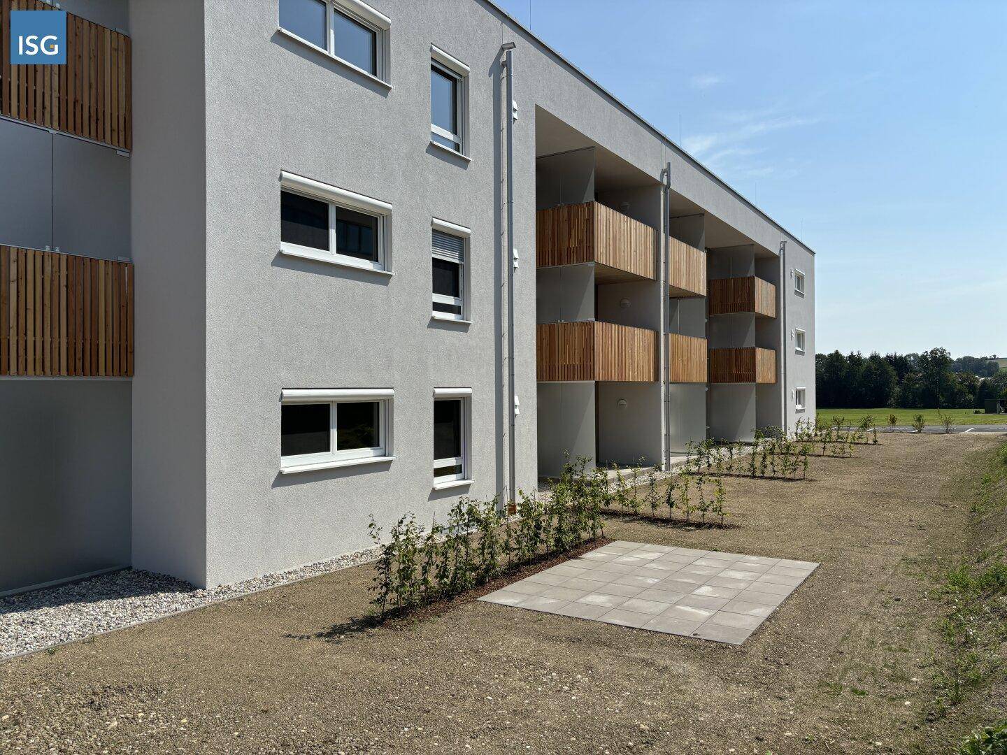Detailansicht der modernen Fassade mit Holzverkleidung an den Balkonen und Rollläden.