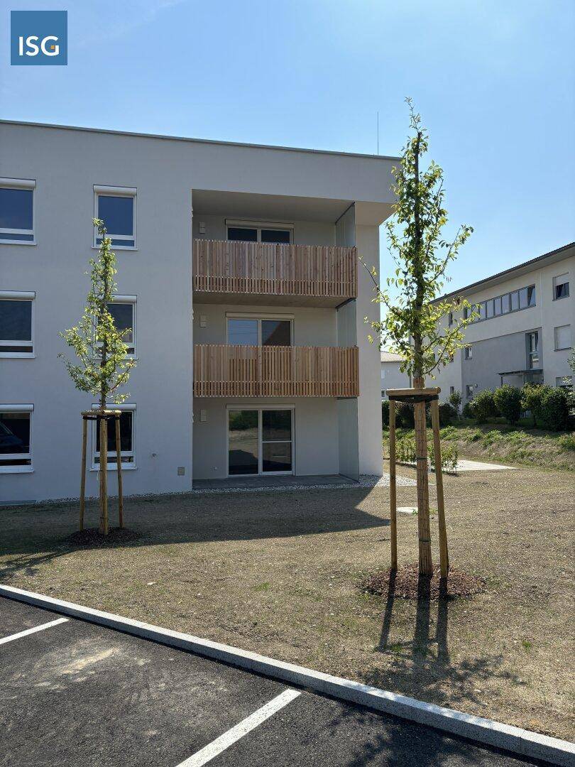Vorderansicht des Neubaus mit jungen Bäumen und einem Teil des zukünftigen Parkplatzes.